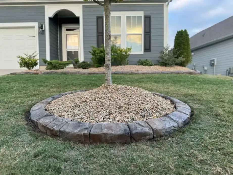 Flagstone stamped curbing around circular garden beds in backyard