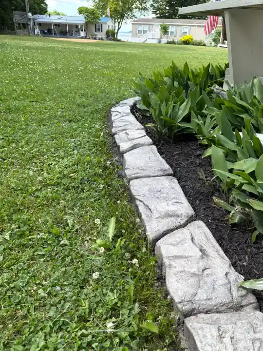 Close-up of stamped rock-pattern curbing edging a planted mulch bed