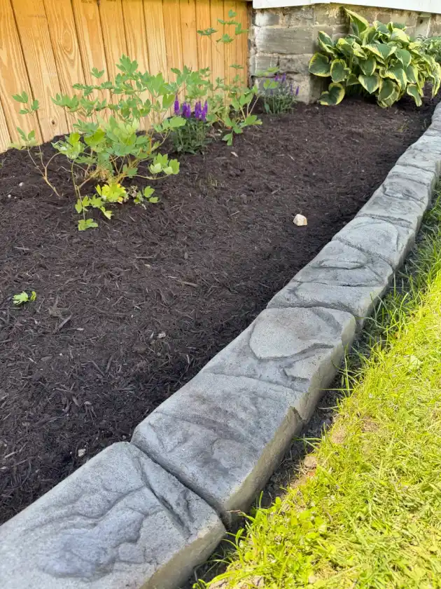 Stamped stone curbing along a sloped mulch garden bed
